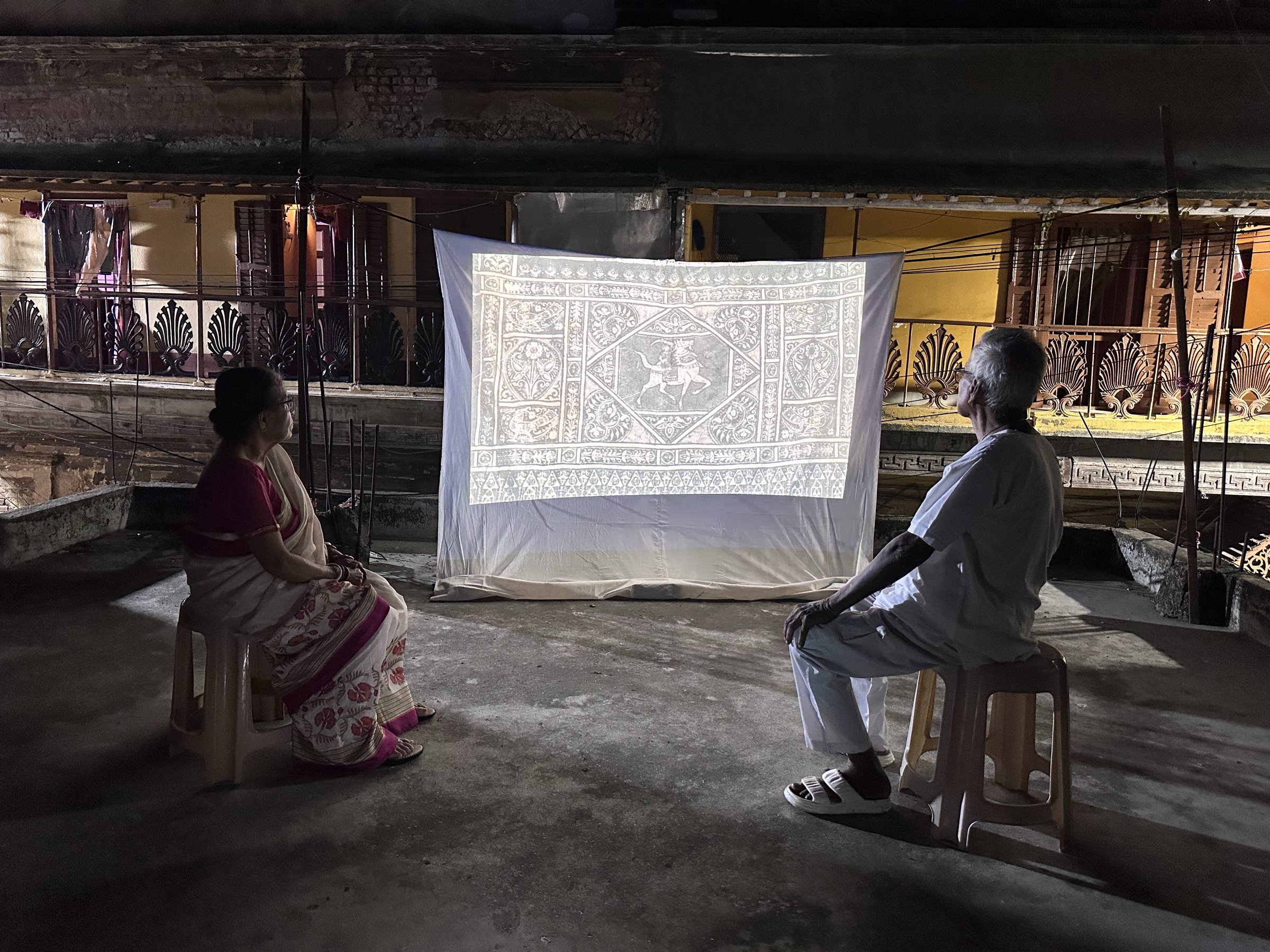 Night projection of a linoleum design onto cloth, on a rooftop in Bagbazar, Kolkata