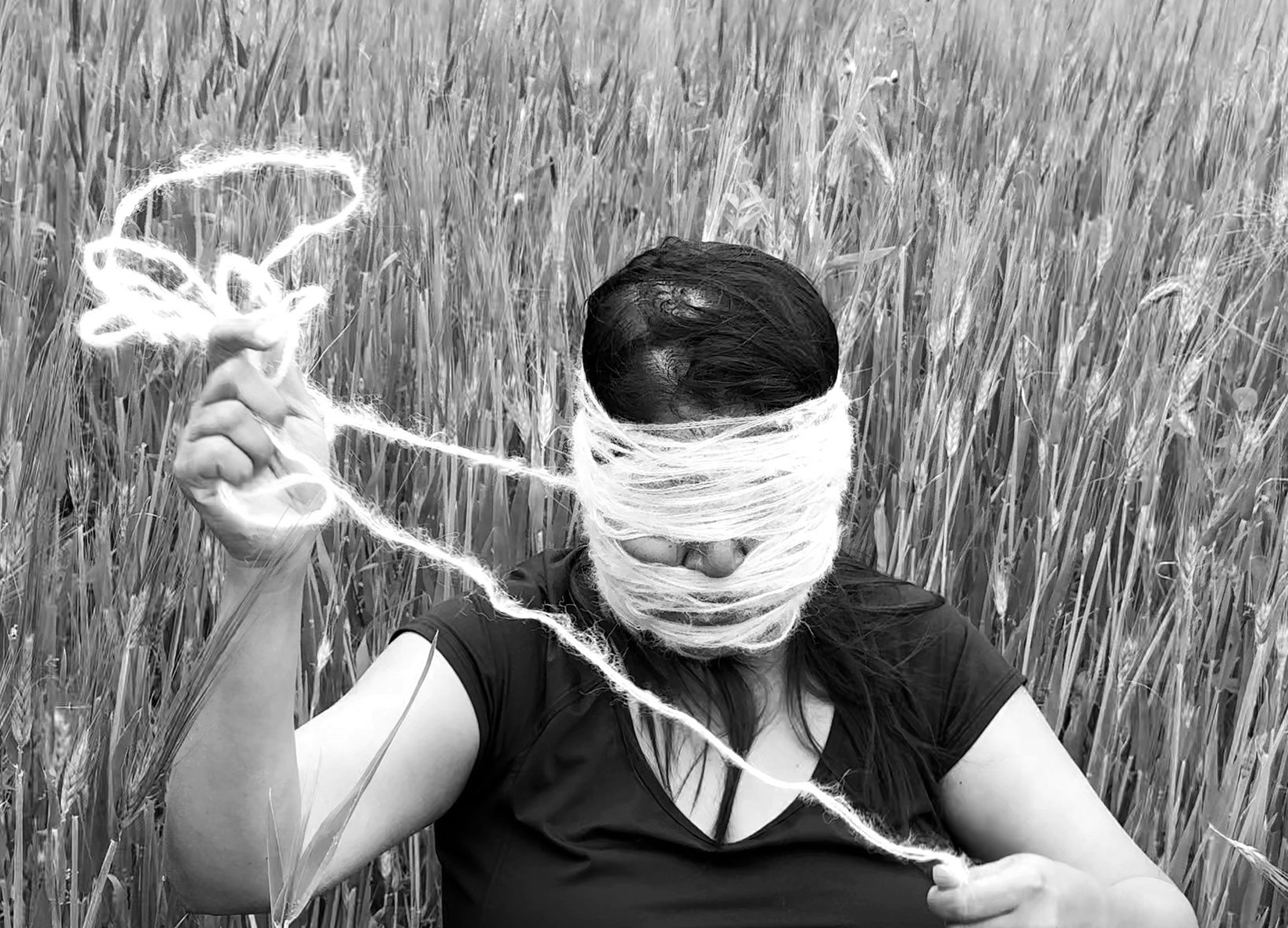 A figure's head wrapped in thread, in black and white
